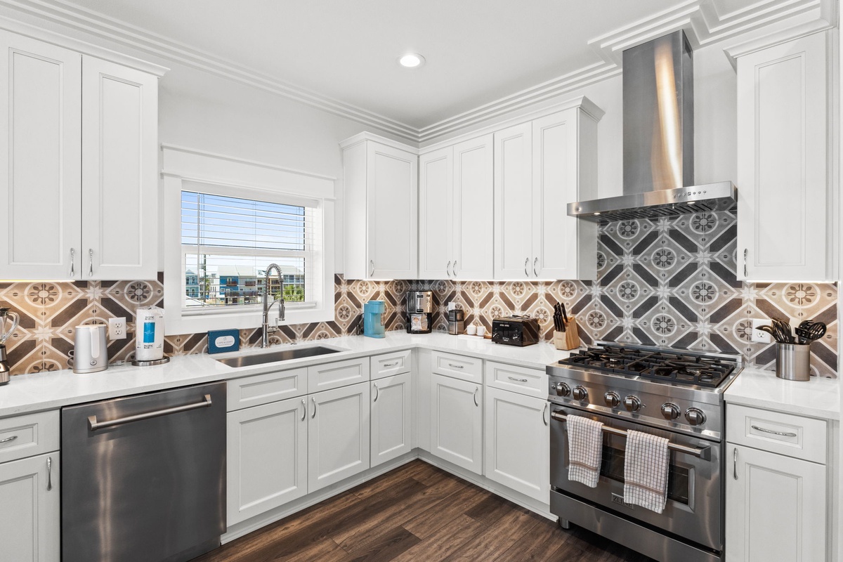 Your gourmet kitchen features white cabinetry, designer tile backsplash, stainless steel appliances, and ample counter space for preparing memorable meals during your stay.