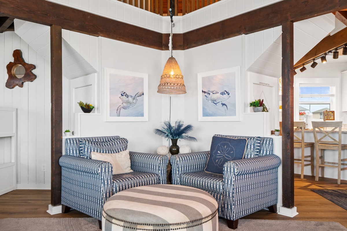Relax in your cozy seating area featuring coastal-inspired decor, exposed beam ceilings, and charming artwork that captures the seaside spirit.