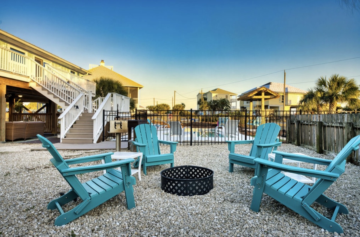 Gather around the fire pit in turquoise Adirondack chairs as the day winds down, with your coastal retreat just steps away.