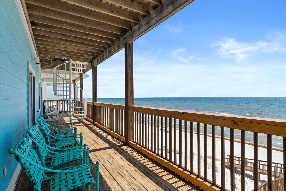 A spacious beachfront balcony overlooking pristine white sand and turquoise waters, featuring inviting seating for relaxing while enjoying the coastal breeze and panoramic sea views.