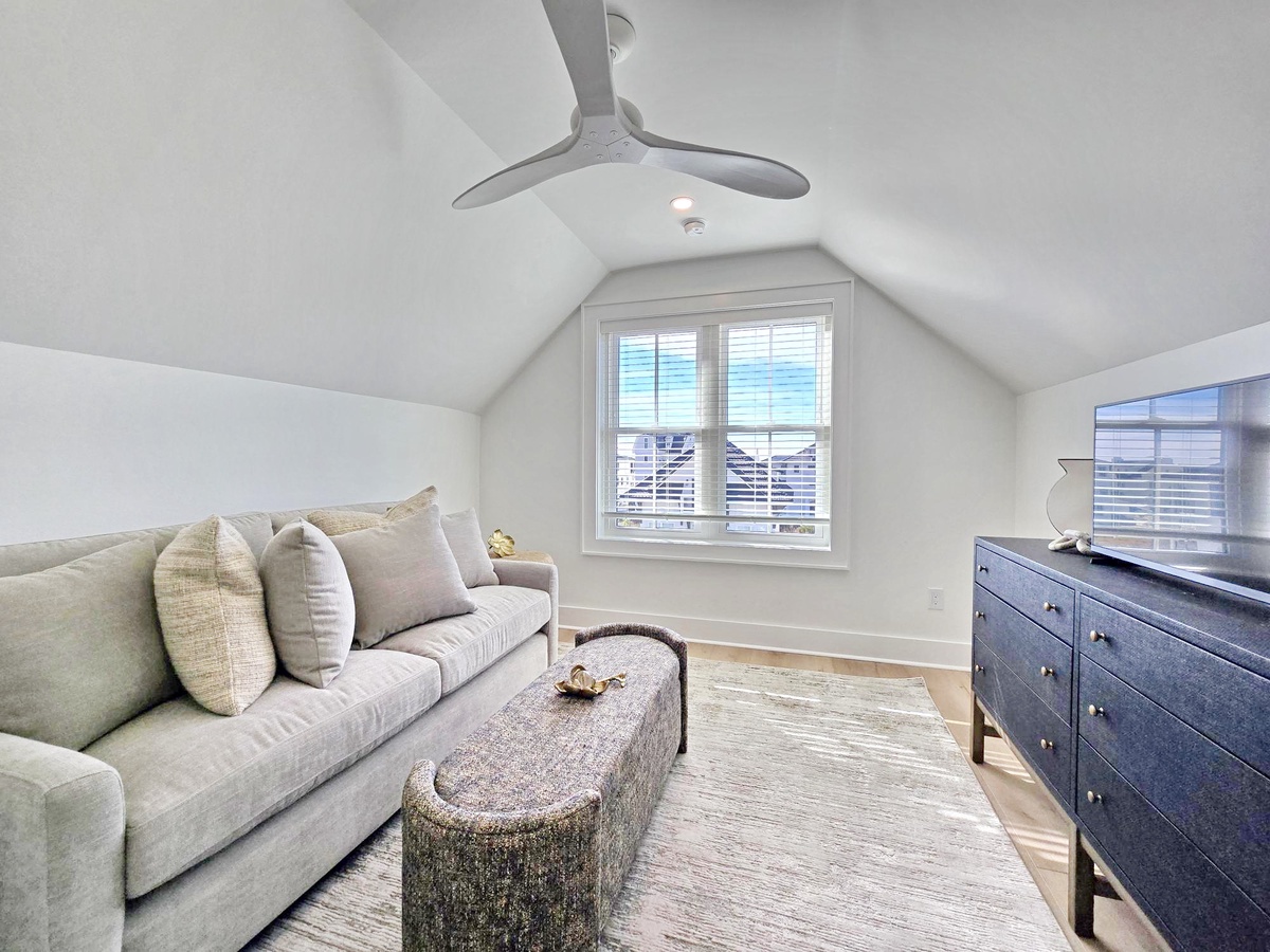 Relax in your cozy loft space with vaulted ceilings, plush seating, and natural light streaming through coastal views.