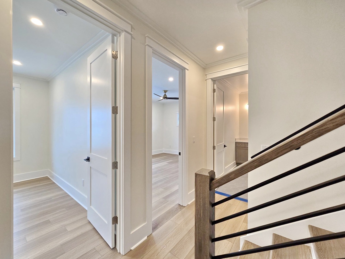 Step into your bright upstairs hallway, where modern design meets comfort with gleaming hardwood floors and elegant white trim.