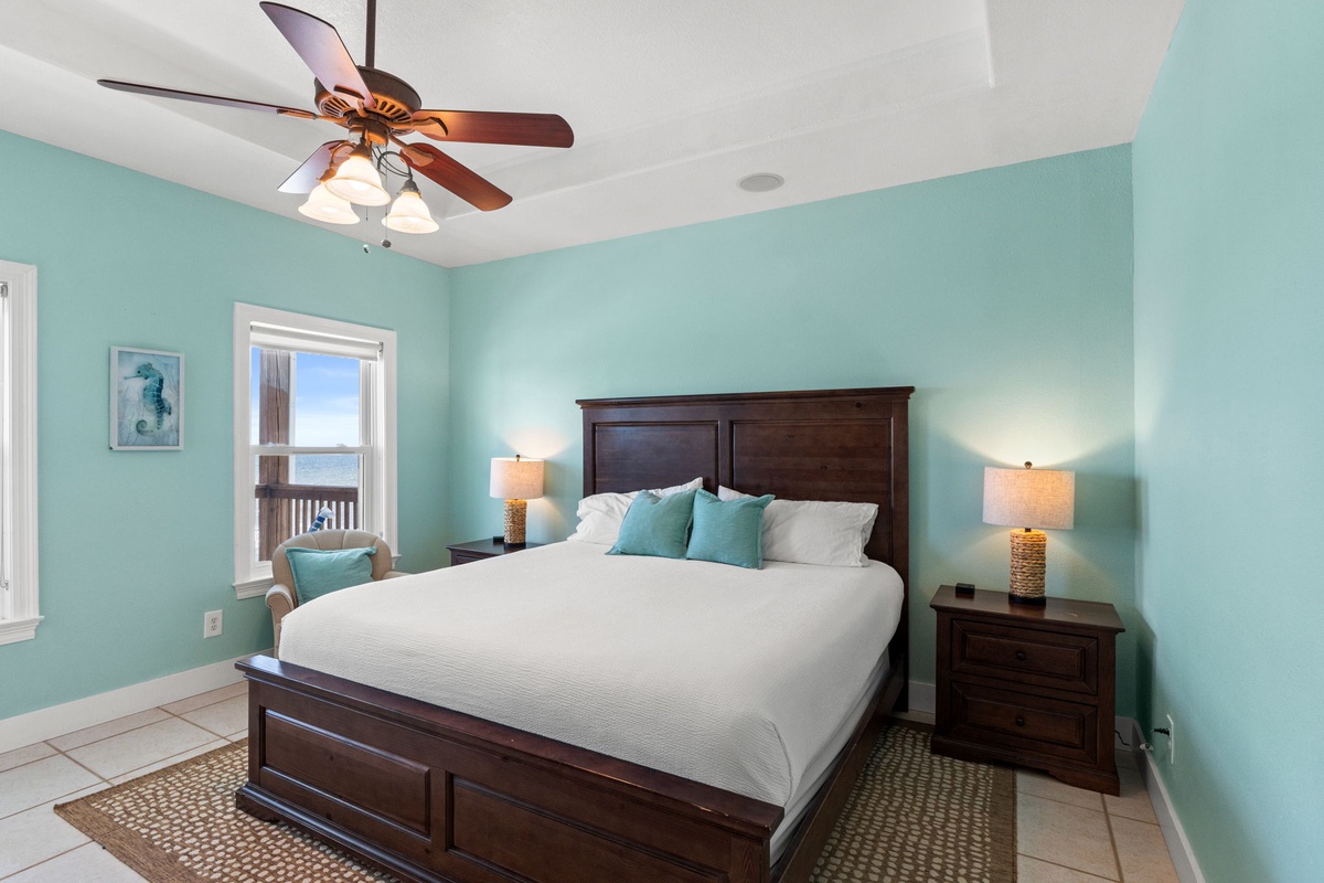 Drift off to sleep in your coastal retreat with calming aqua walls, crisp linens, and gentle ceiling fan breezes. Wake to serene water views through the window.