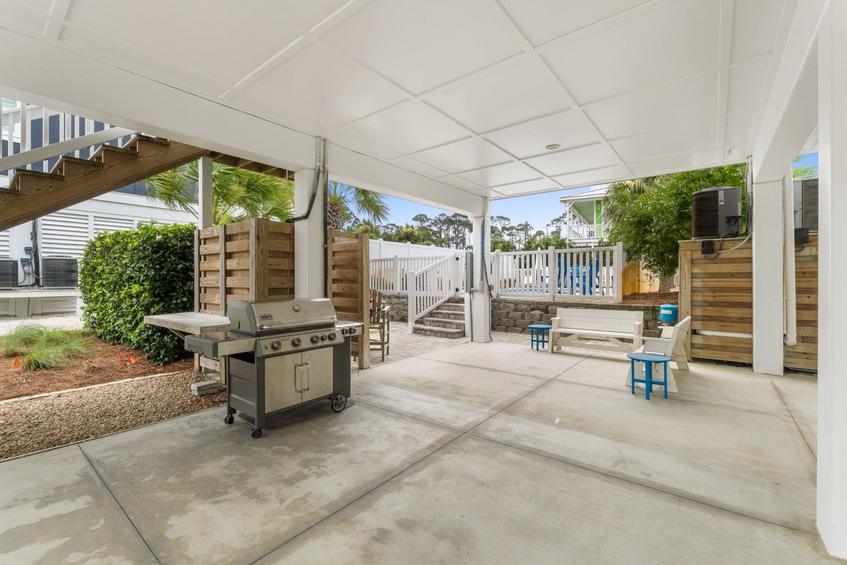 Your private covered patio features a premium gas grill and colorful seating, perfect for casual outdoor dining and relaxed gatherings under the coastal breeze.