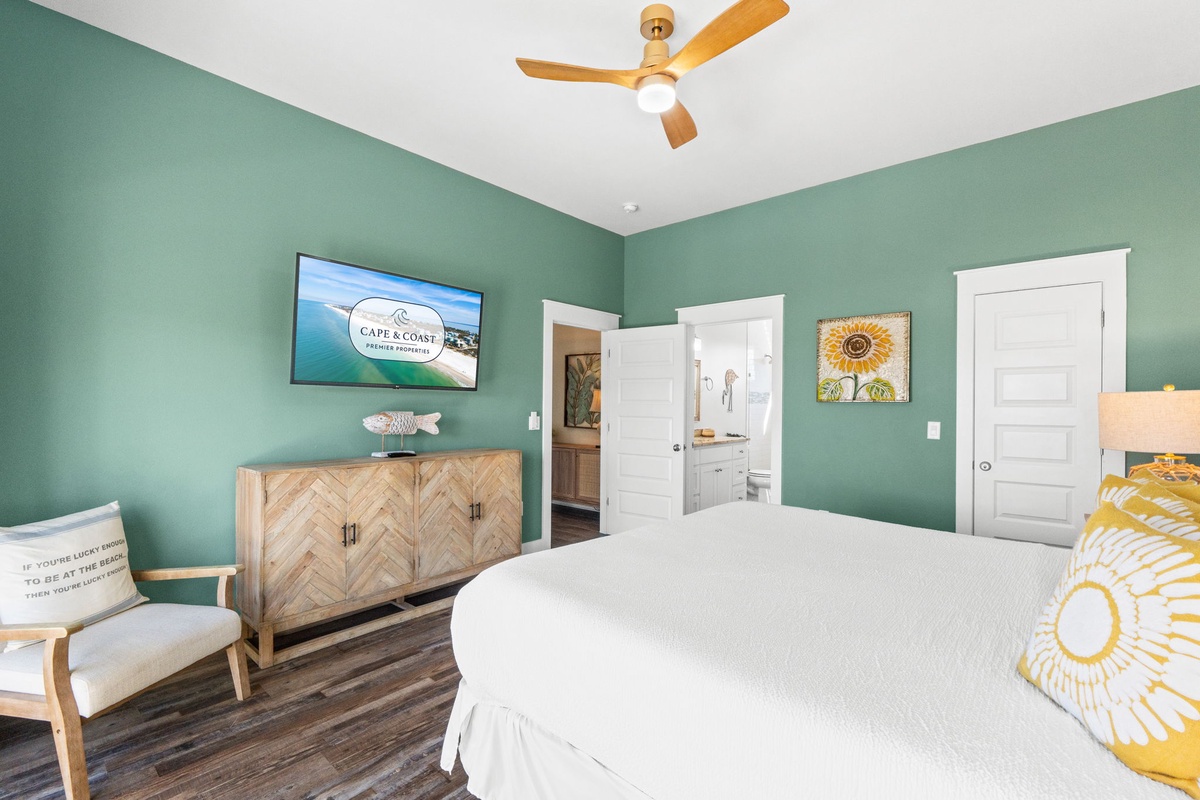 Sink into crisp white linens in your tranquil green retreat, where coastal breezes from the ceiling fan create the perfect sleep sanctuary.