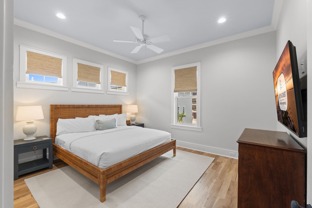 Unwind in this serene bedroom with plush bedding, soft natural light, and a ceiling fan to keep you comfortable. A mounted TV and modern touches create your perfect retreat.