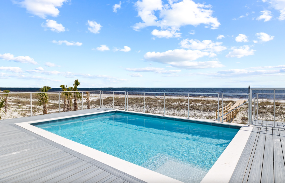 Beachfront pool deck with pristine ocean views and private beach access through wooden boardwalk.