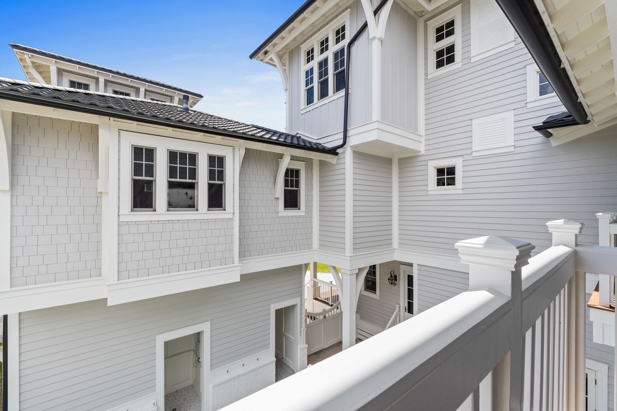 A charming interior courtyard design framed in crisp white finishes and coastal-style shingle accents creates an inviting architectural flow between your rental's spaces.