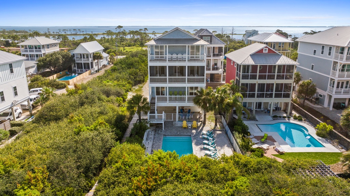 Aerial view of this coastal property and its surrounding beachside neighborhood, showcasing the multiple private pools and easy access to the waterfront area.