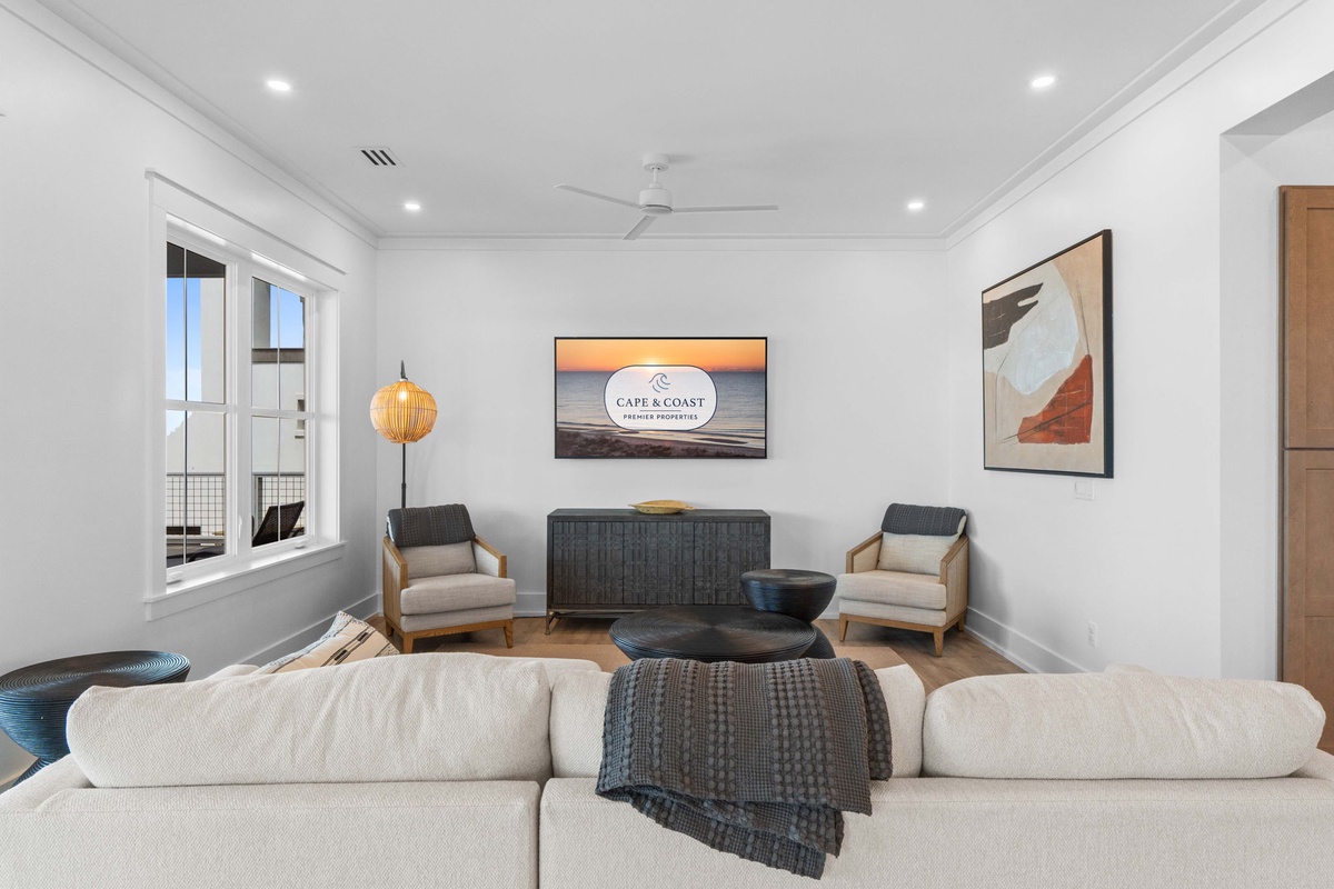 Sink into the plush sofa and unwind in this bright living space with coastal accents, modern art, and an inviting view that draws the eye outdoors.