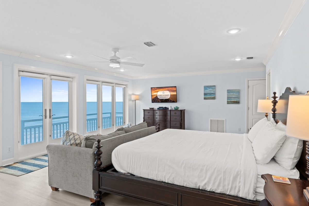 Wake up to stunning ocean views from your private balcony in this bright, airy bedroom with plush bedding and coastal charm.