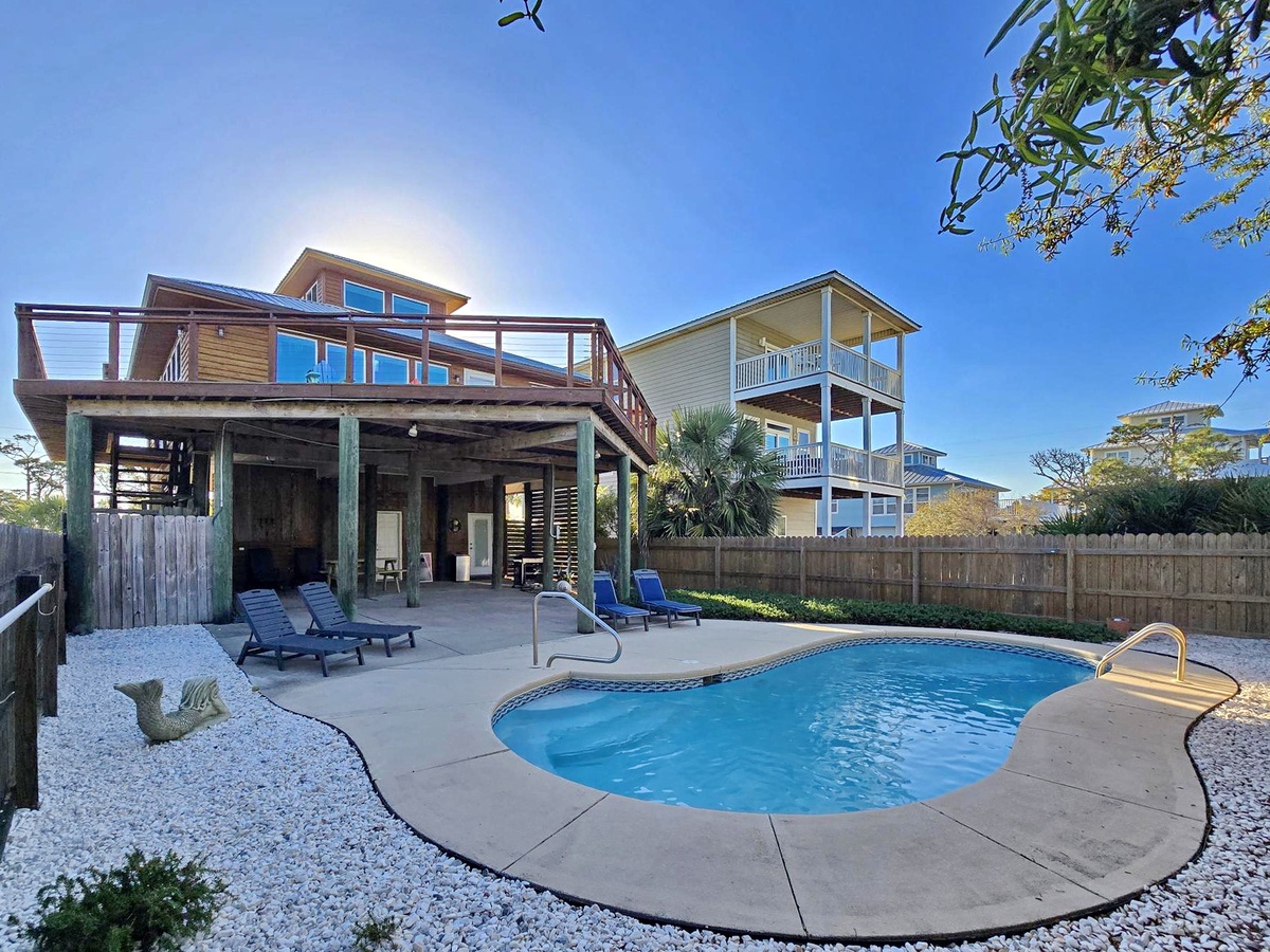 Modern coastal home with private pool, outdoor loungers, and covered patio perfect for relaxing under sunny skies.