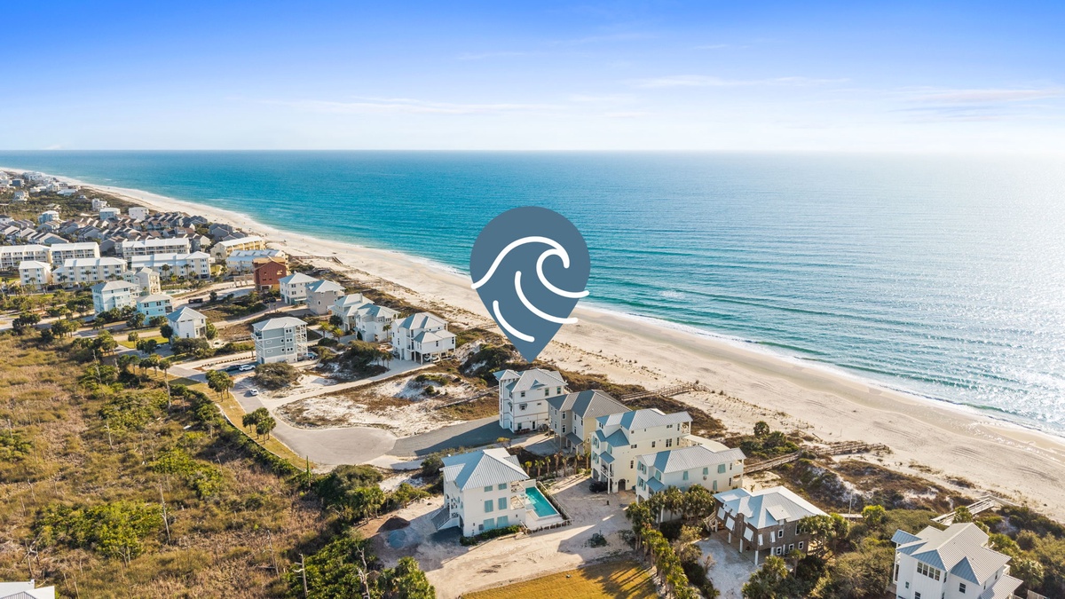 Stunning aerial view of beachfront vacation homes nestled between pristine white sand and turquoise waters.