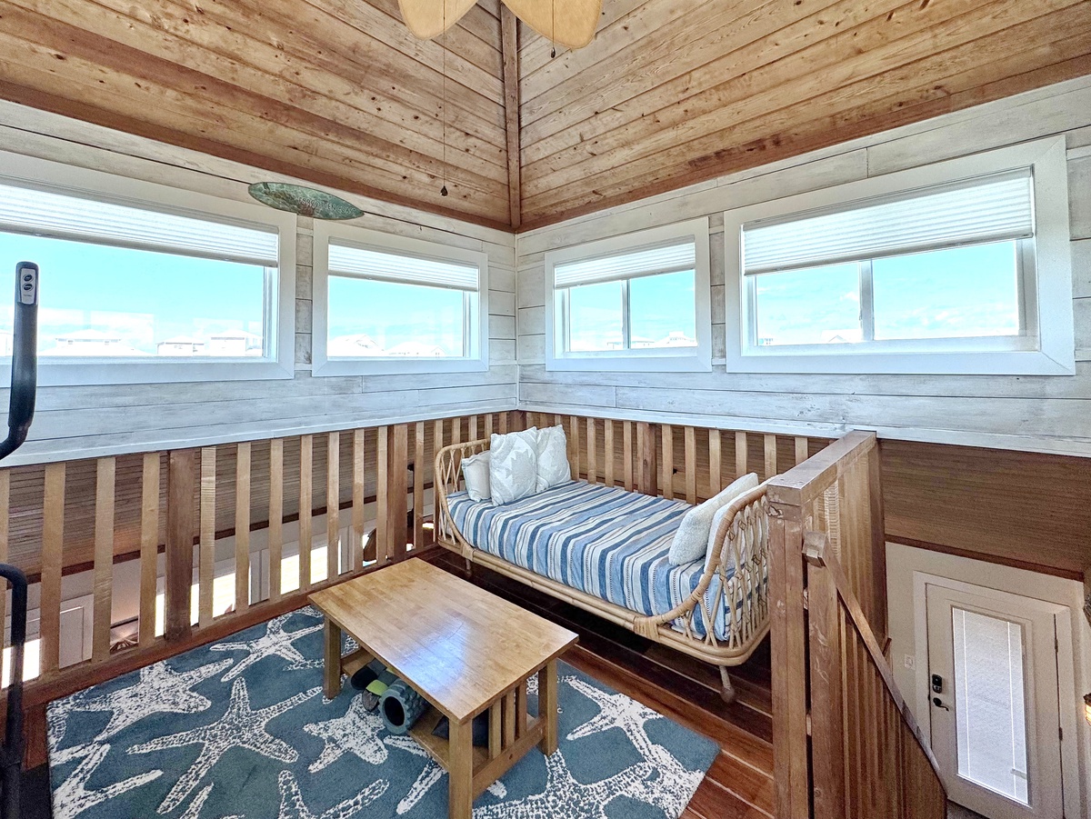 Your cozy loft reading nook offers stunning mountain views through wraparound windows, complete with comfortable seating and natural wood charm.