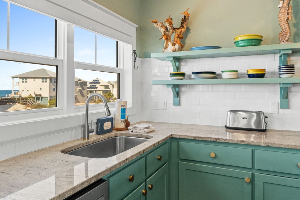 You'll love preparing meals in this bright coastal kitchen with turquoise cabinets and stunning ocean views through the window.