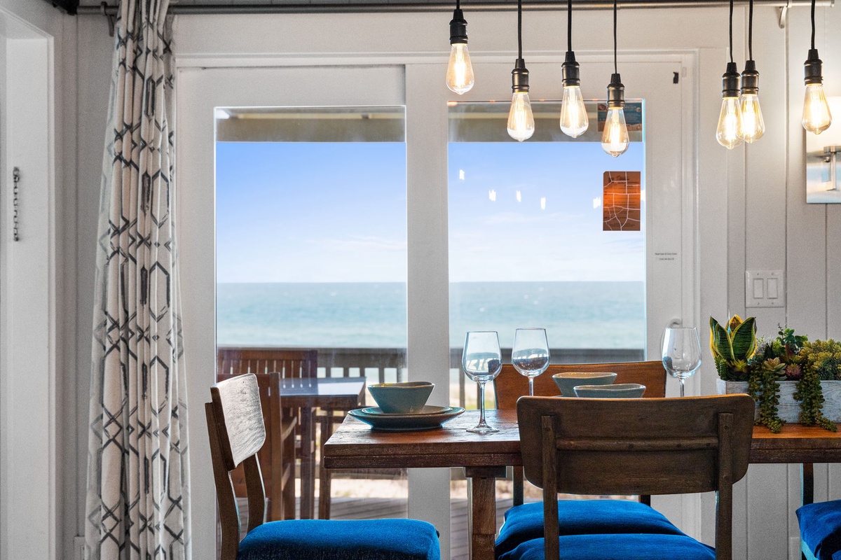 Picture yourself dining with endless ocean views framing every meal. Edison bulbs cast a warm glow over your table while the sea breeze drifts through the open door.