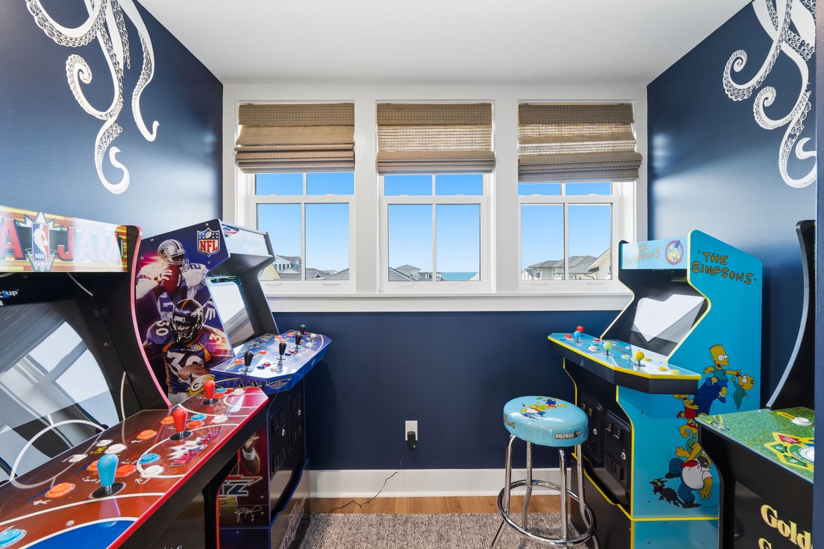Your private game room awaits with classic arcade machines and nautical-themed decor, flooded with natural light from oversized windows framing neighborhood views.