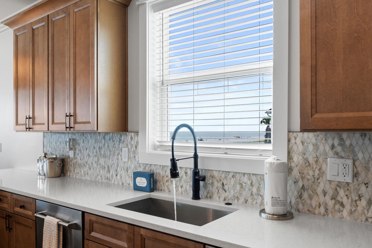 Bright kitchen space with warm wood cabinets and elegant tile backsplash, ready for meal prep and morning coffee with natural light streaming through the window.