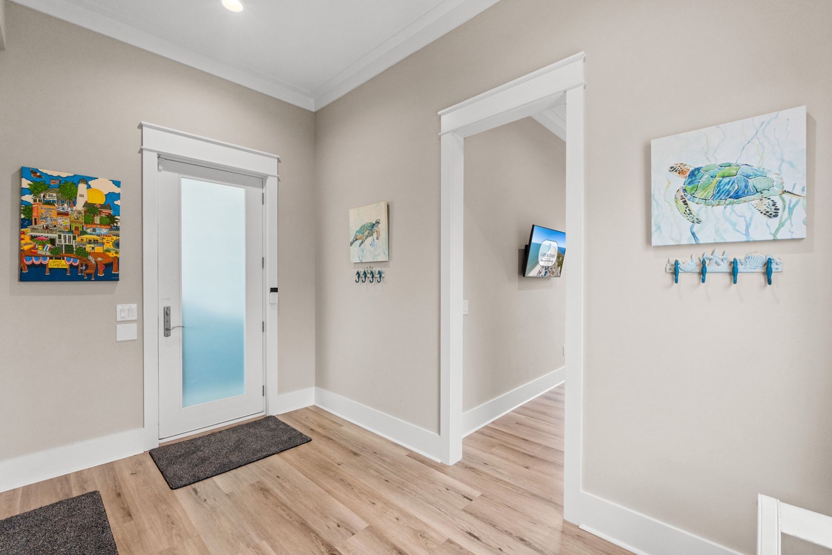 Step into a bright, welcoming entryway where coastal charm greets you at the door. Warm wood floors and cheerful beach-themed art set the tone for your relaxing stay.