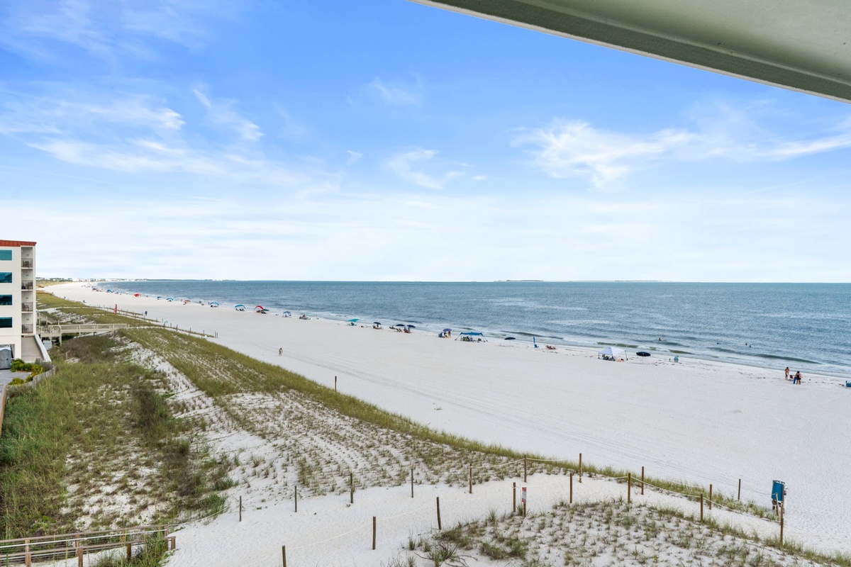 This balcony offers sweeping views of pristine white sand beach and turquoise waters, where you can watch waves roll in and beachgoers stroll the shore below.