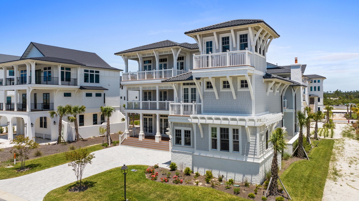 A striking coastal vacation home featuring multiple balconies and palm-lined grounds in a residential beach community.