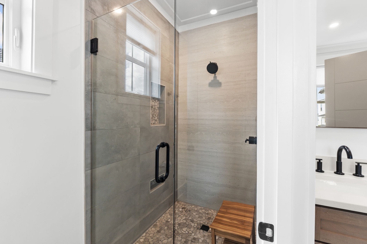 Your spa-like bathroom features a stunning walk-in shower with elegant stone tiles and a convenient teak bench for ultimate relaxation.
