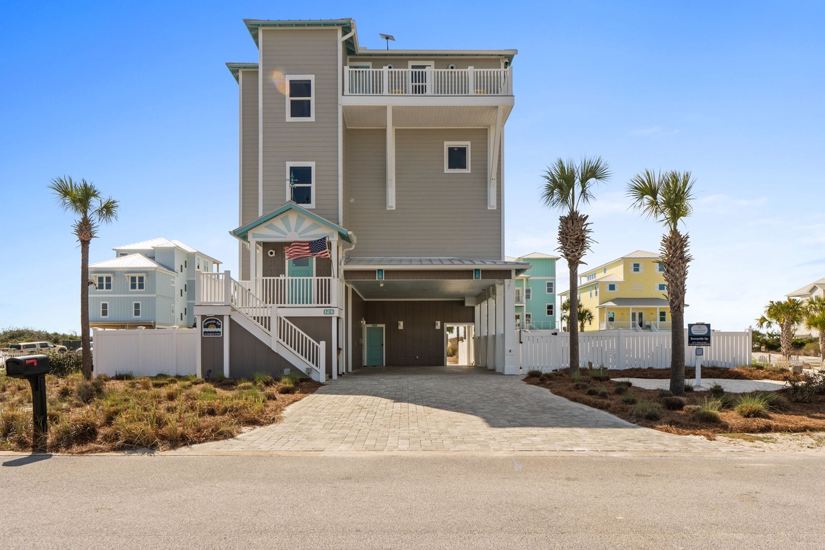 Modern beach house with elevated design, palm trees, and covered parking in coastal neighborhood setting.