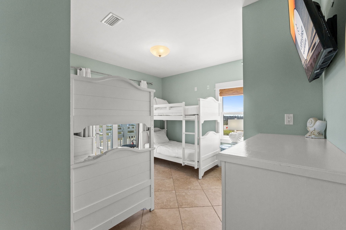 Your kids will love this cheerful bunk room with crisp white beds and soothing coastal colors, perfect for creating vacation memories.