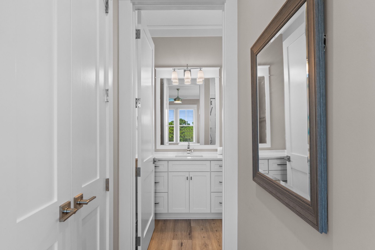 Step into your private retreat, where crisp white cabinetry and warm wood floors create a fresh, welcoming space for your morning routine.