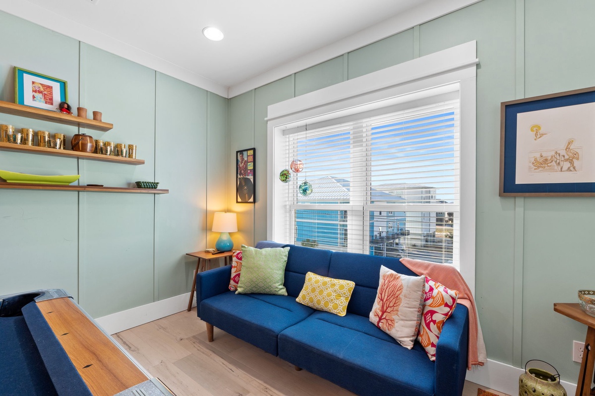 Sink into the plush navy sofa with colorful pillows, surrounded by soothing mint walls and thoughtful touches that make this your perfect retreat.