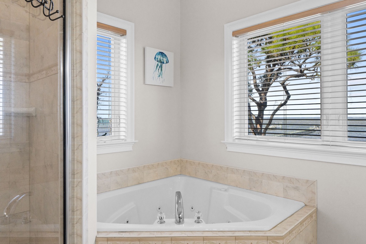 Unwind in your private corner jetted tub, surrounded by natural light and soothing coastal artwork for the perfect relaxing retreat.