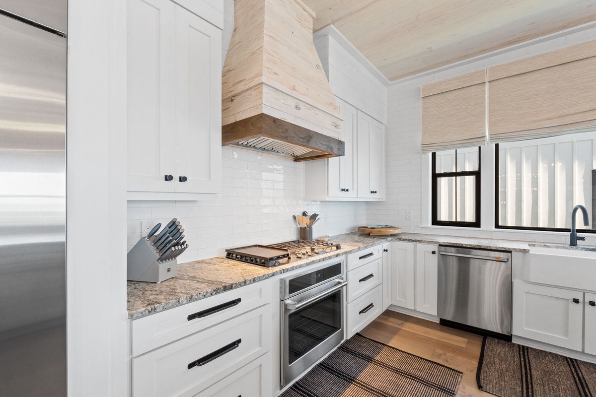 Your chef-ready kitchen awaits with granite countertops, stainless steel appliances, and warm wood beam ceiling creating the perfect culinary retreat.