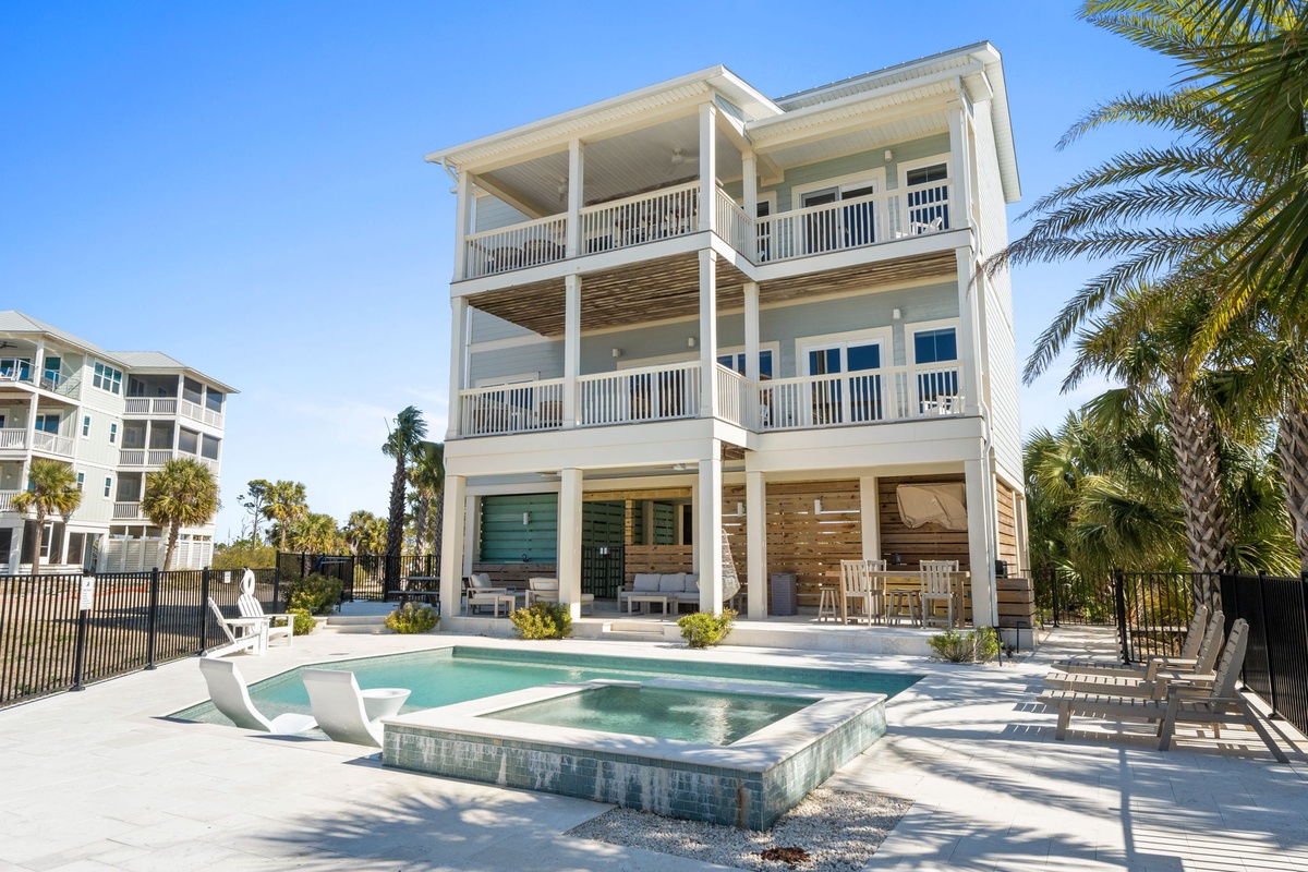 Modern three-story beachside property featuring private pool, hot tub, and tropical landscaping in a coastal community setting.