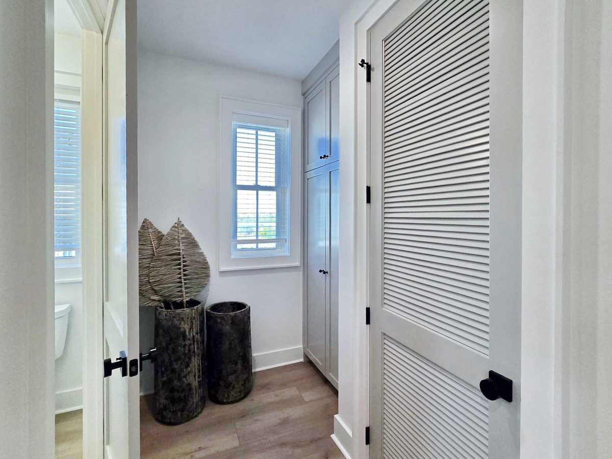 Step into your bright, organized hallway with elegant storage solutions and natural light streaming through shuttered windows.