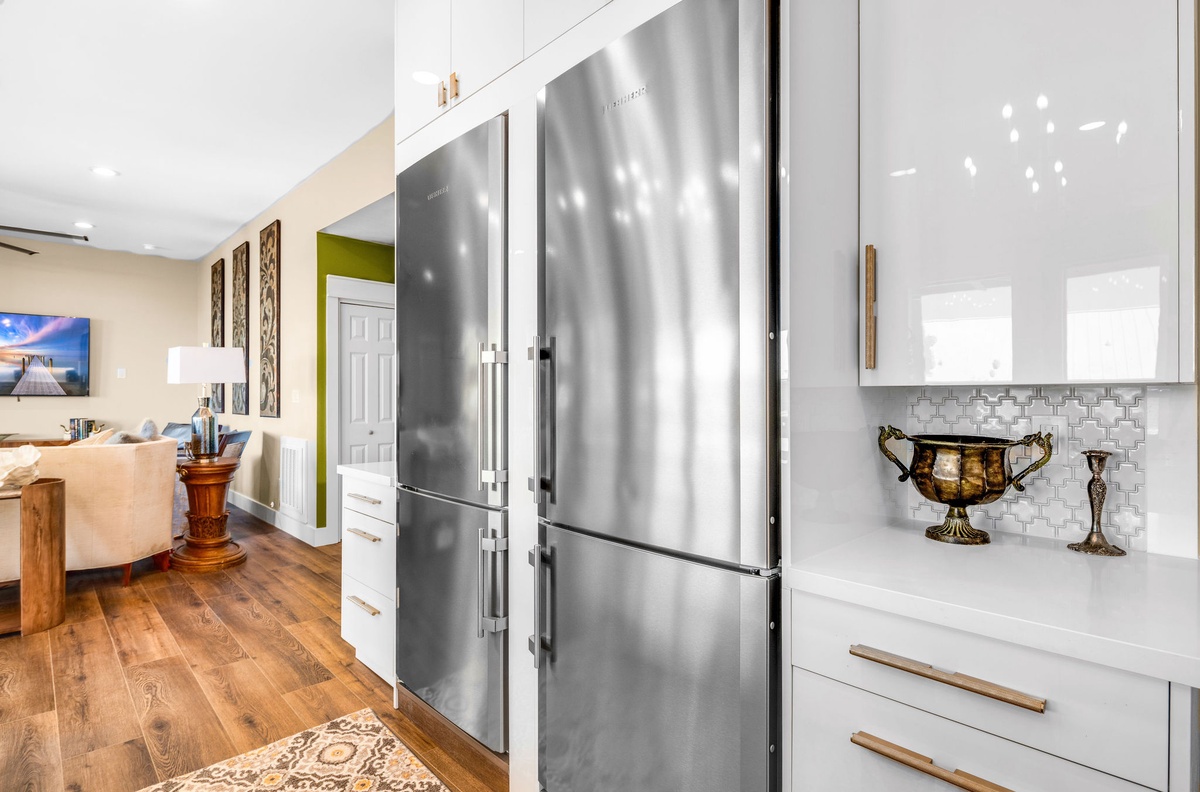 Prepare your favorite meals in this sleek kitchen featuring stainless steel appliances, marble countertops, and elegant white cabinetry.