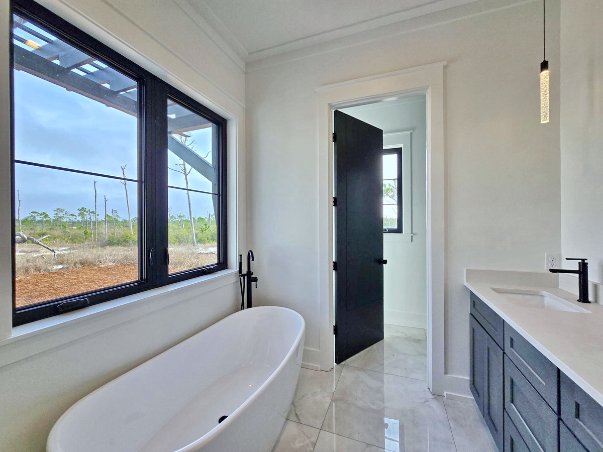 Soak away stress in your elegant freestanding tub while enjoying peaceful countryside views through expansive windows.