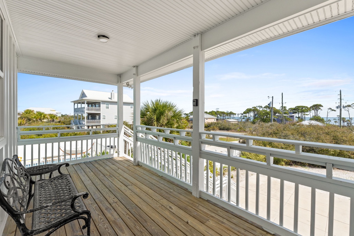 Your covered balcony invites peaceful mornings with coffee, overlooking natural coastal surroundings and charming beach homes.