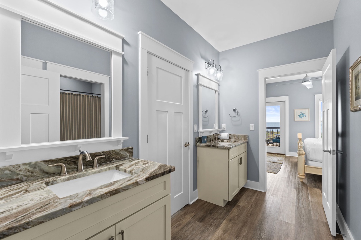 Step into your elegant bathroom with dual vanities, marble countertops, and crisp white cabinetry that makes your morning routine feel luxurious.