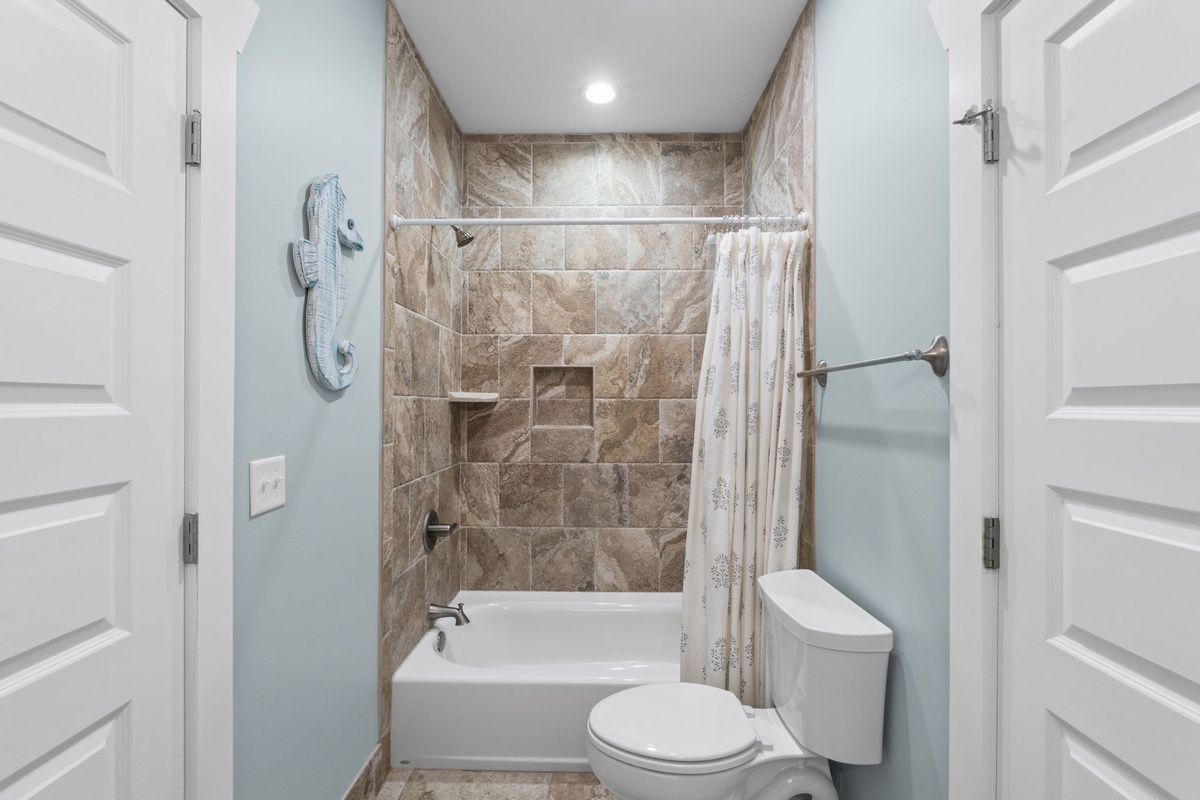 Step into your private bath with spa-inspired tile, a soaking tub, and coastal blue walls that make every moment feel like a refreshing retreat.