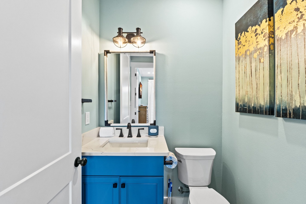 Refresh in your stylish powder room with calming mint walls, bold blue vanity, and warm nautical lighting.