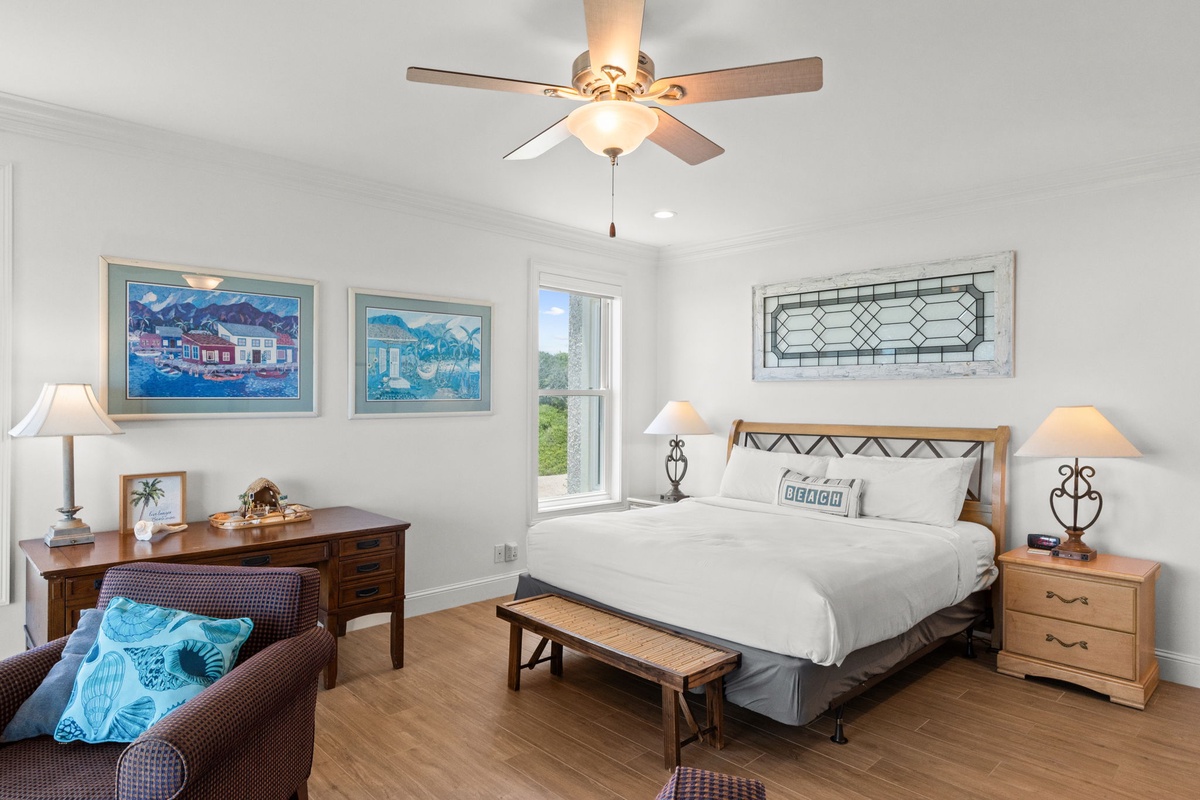 Relax in this coastal-inspired retreat with crisp linens, nautical artwork, and a ceiling fan to keep you comfortable. Sunlight streams through the window, inviting you to unwind after your beach adventures.
