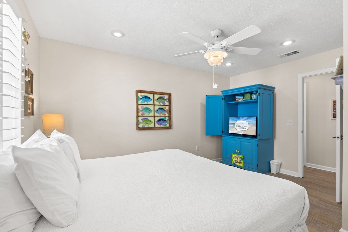 Drift off in your coastal-themed bedroom with crisp white linens and tropical fish art creating a peaceful seaside atmosphere.