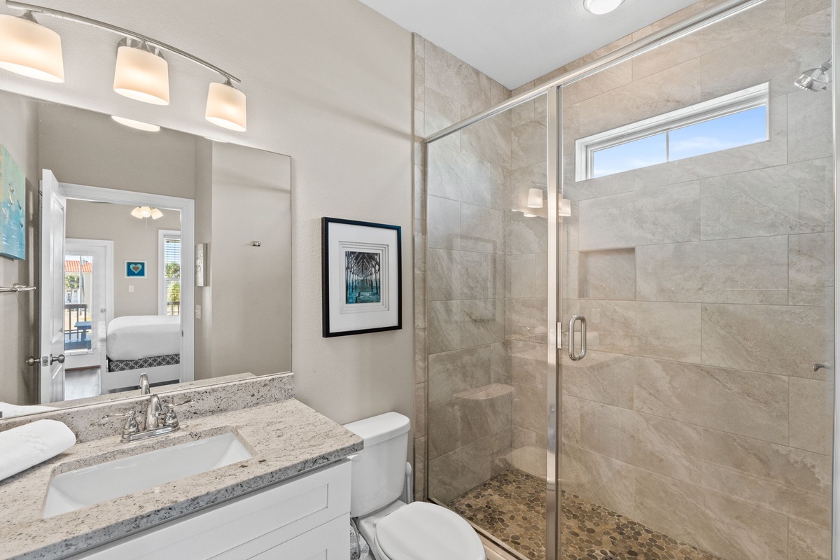 Unwind in your elegantly appointed bathroom featuring a spacious walk-in shower with premium stone tiling and granite vanity countertops.