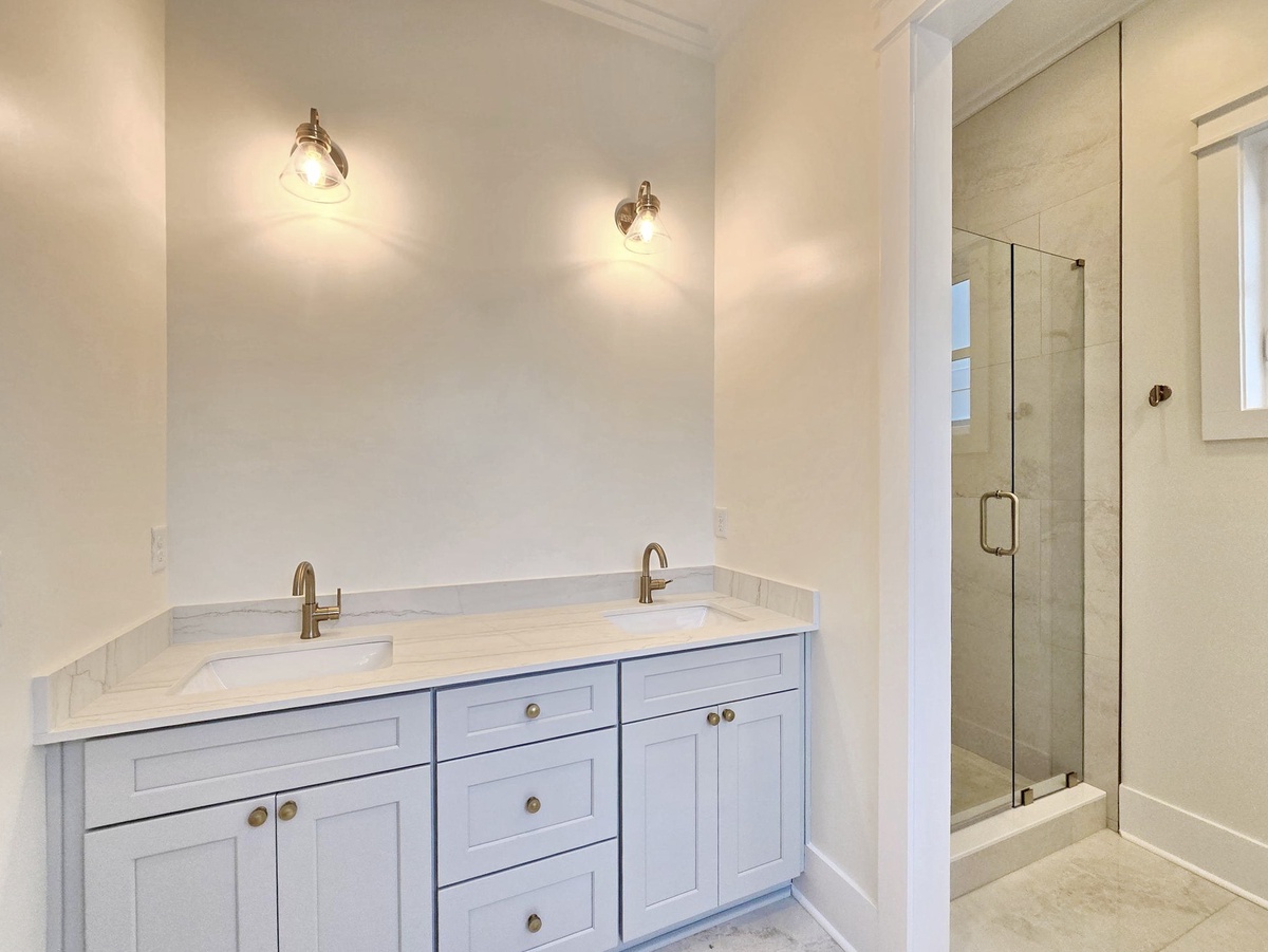 Your elegant ensuite features dual vanity sinks and a pristine glass shower, creating the perfect morning routine space.