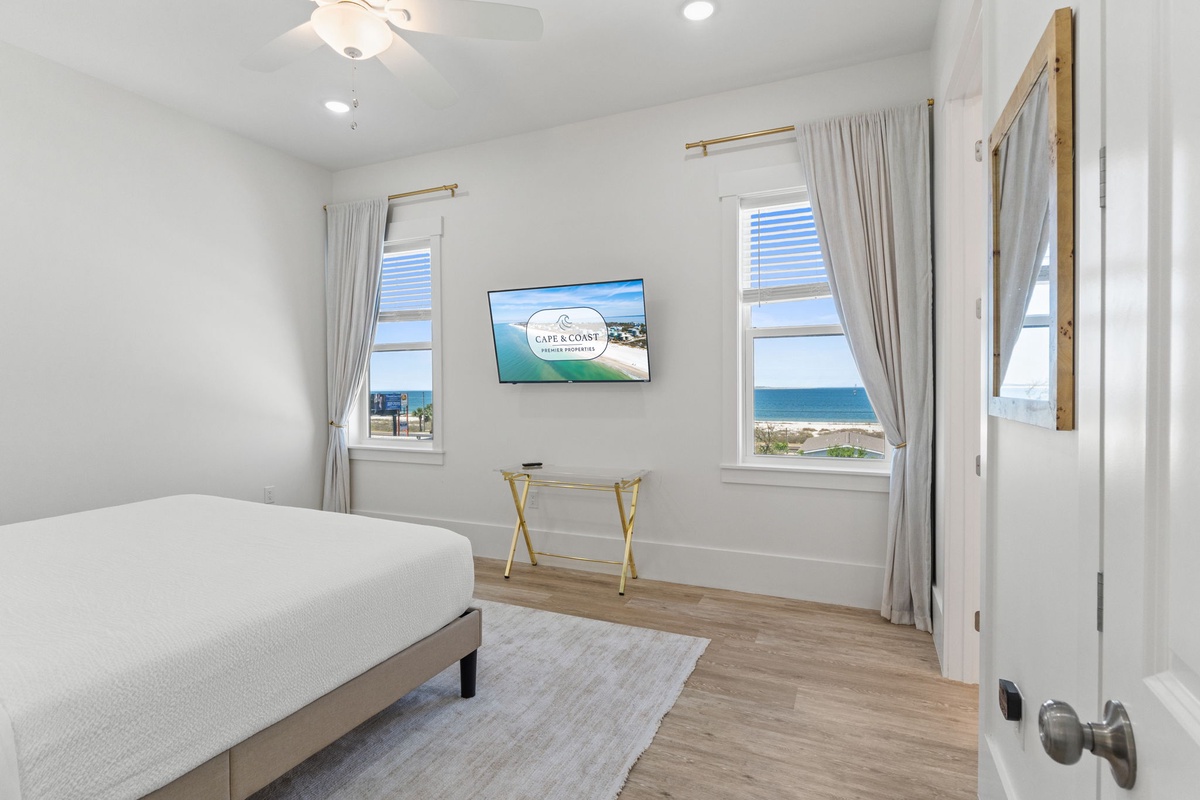 Your bright bedroom features ocean views, flat-screen TV, and modern furnishings for the perfect coastal getaway.