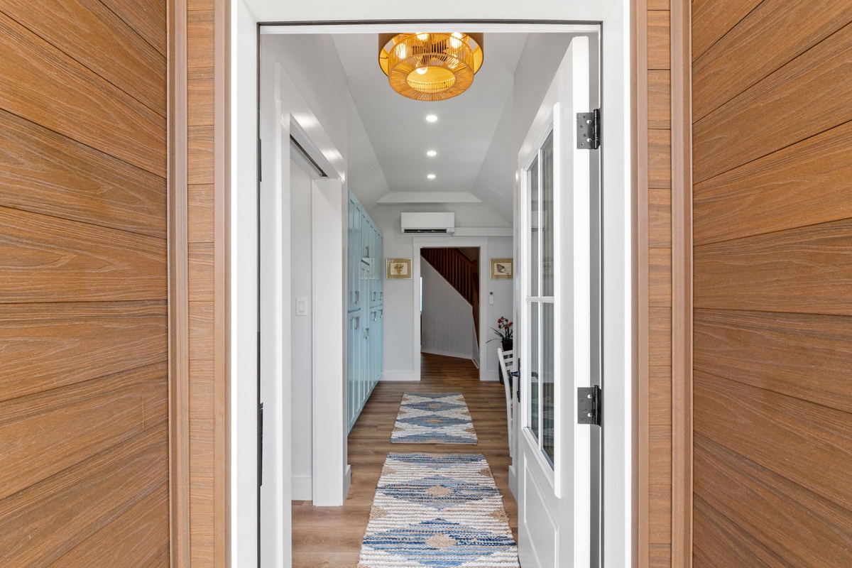 Step into your welcoming hallway, where warm wood-toned doors and a golden pendant light set the tone for your coastal getaway. Clean lines and thoughtful details create an inviting first impression.