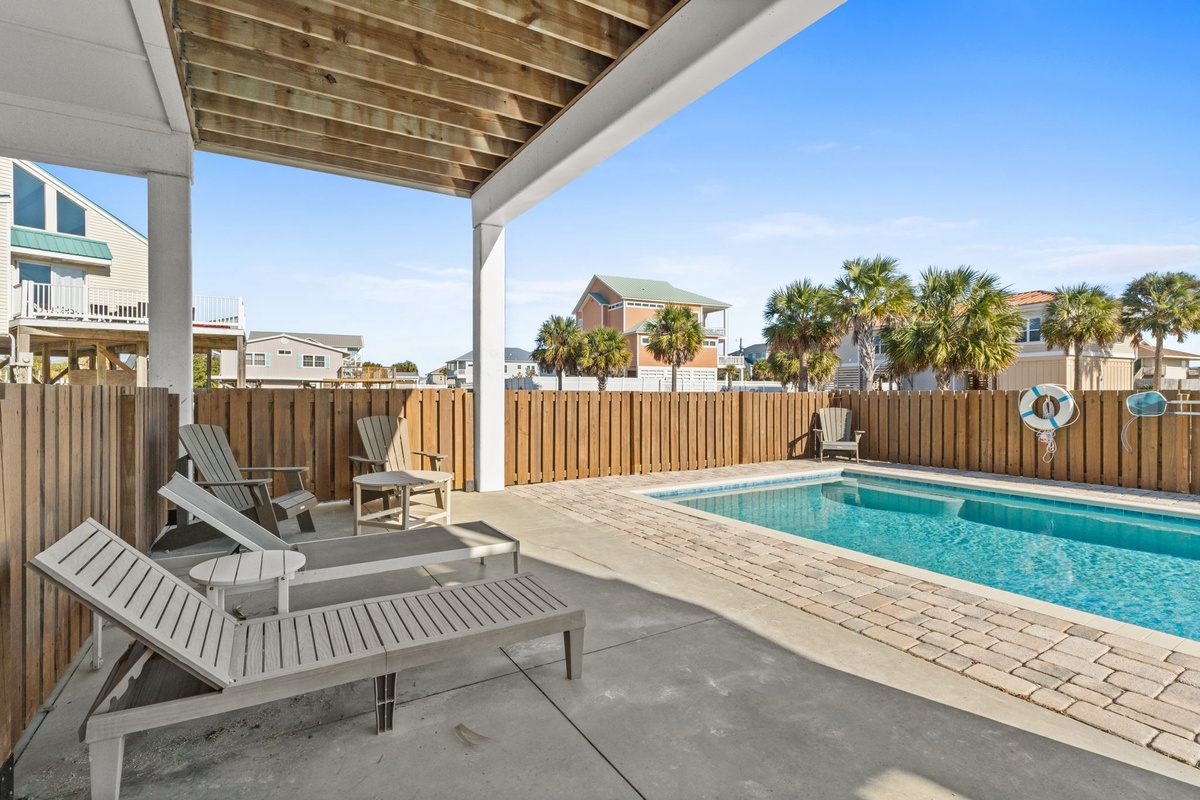 Your private poolside retreat awaits with comfy loungers under a covered patio, perfect for relaxing between refreshing swims.