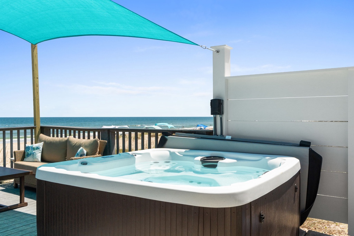 Soak under the shade sail while gazing at turquoise waters and soft sands. Your private hot tub offers the perfect beachfront escape for ultimate relaxation.