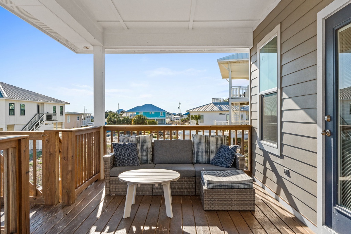 Relax on your private balcony with comfortable seating and peaceful neighborhood views stretching beyond the coastal community.