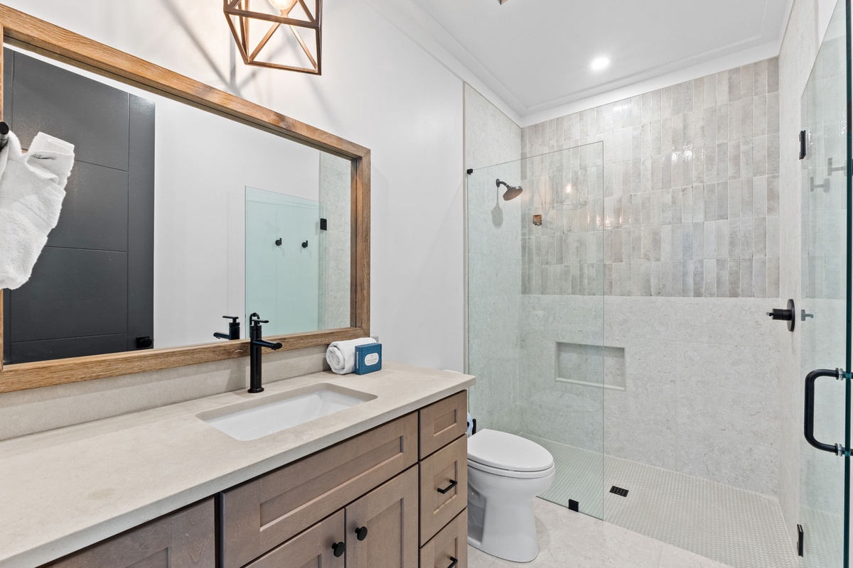 Sink into relaxation in this beautifully tiled shower, styled with modern fixtures and a wood-framed vanity. Coastal-inspired details make every moment feel like a retreat.